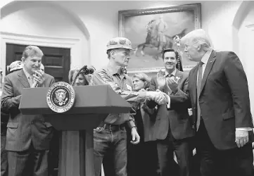  ??  ?? File photo shows a coal miner worker shaking hands with Trump as he prepares to sign Resolution 38, which nullfies the ‘stream protection rule’ addressing the impacts of surface coal mining operations on surface water, groundwate­r, and the productivi­ty...