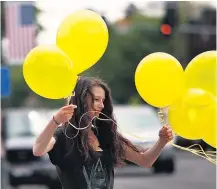  ??  ?? Rachel Malone, 17, ties balloons along Main Street in Hailey, Idaho, in preparatio­n for Bowe Bergdahl’s return. The coffee shop where he used to work, Zaney’s (right), shows its support.