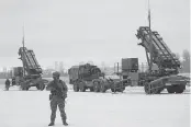  ?? JANEK SKARZYNSKI TNS ?? An armed soldier stands watch in front of American Patriot missile launchers during a military exercise at Warsaw Babice Airport, Poland, in February.