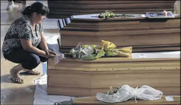  ?? GREGORIO BORGIA / ASSOCIATED PRESS ?? A woman inside a gymnasium in Ascoli Piceno, Italy, touches a coffin Friday containing one of the victims of Wednesday’s earthquake in the central part of the country. The gym has 34 caskets lined up for a funeral Mass today.