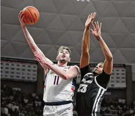  ?? Jessica Hill/Associated Press ?? UConn’s Alex Karaban (11) shoots around Providence’s Bryce Hopkins (23) on Feb. 22 in Storrs.