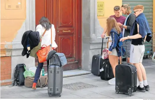  ?? JAVIER ALBIÑANA ?? Un grupo de turistas espera en la puerta de una vivienda turística de Málaga.