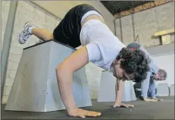  ?? JOHN MAHONEY/Postmedia News ?? Exercisers perform handstand pushups at a CrossFit workout in Dorval, Que.