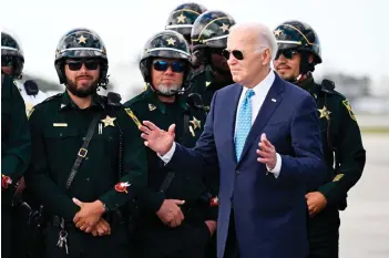  ?? — AFP photo ?? Biden (second right) greets law enforcemen­t officers before boarding Air Force One at Palm Beach Internatio­nal Airport in West Palm Beach, Florida.