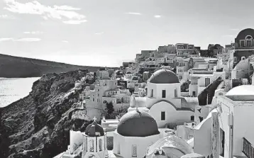  ?? TRISH FEASTER/RICK STEVES’ EUROPE ?? The picturesqu­e village of Oia on Santorini, built atop a volcanic crater, is awash in white and blue.