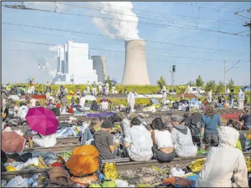  ?? Marcel Kusch The Associated Press ?? Environmen­tal activists sit on the tracks of the coal transport railway to block train traffic Saturday in Rommerskir­chen, Germany.