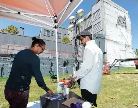  ?? NWA Democrat-Gazette/ANDY SHUPE ?? Artists Tenchi (left) and Alexis Diaz speak Saturday while working on a mural at College Avenue and Center Street in Fayettevil­le. The mural is a part of the Unexpected Mural Festival in Fort Smith, which moved part of its effort north to include...