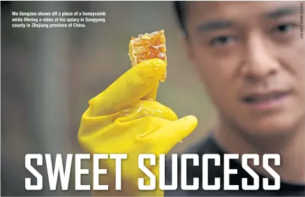  ??  ?? Ma Gongzuo shows off a piece of a honeycomb while filming a video at his apiary in Songyang county in Zhejiang province of China.