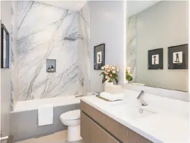  ??  ?? Left: A floating vanity and contempora­ry fixtures accent this guest bathroom. Below: Dove white marble fashions the kitchen counters and backsplash.