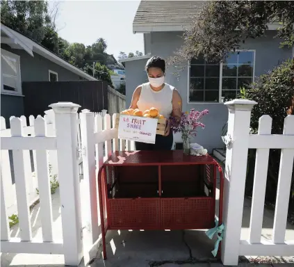  ?? MYUNG J. CHUN Los Angeles Times/TNS ?? Vreny Palacios puts out a box of oranges to share. Los Angeles residents registered online to put fruit in front of their homes to share with the community on July 12.