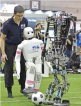  ??  ?? Robots take part in an adult-size category football match.