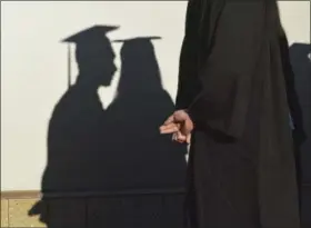  ?? BERNARD THOMAS — THE HERALD-SUN VIA AP, FILE ?? University graduates cast shadows on a wall before a commenceme­nt in Durham, N.C. In its June 2017 issue, a leading journal of political philosophy took up the Black Lives Matter movement without a single contributi­on from a black academic, triggering...