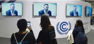  ??  ?? Making sense: Visitors to the UN climate conference watching a speech by Schwarzene­gger in Katowice, Poland. — AP