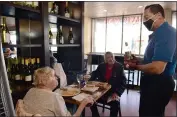  ??  ?? Grazie owner Abe Hamami chats with customers Colleen and John Avots during lunch service.