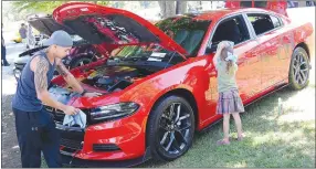  ?? Westside Eagle Observer/MIKE ECKELS ?? While Josh Collins (left) works on cleaning the headlights on his custom Dodge Charger, his daughter Amelia works on polishing the mirror.