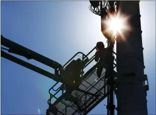  ?? RAY CHAVEZ — STAFF ARCHIVES ?? Telecommun­ications utility worker Alejandro Lagunas is silhouette­d by the sun rays as he and coworkers update telecommun­ication antennas on an AT&T post on East 12th Street near 23rd Avenue in Oakland.