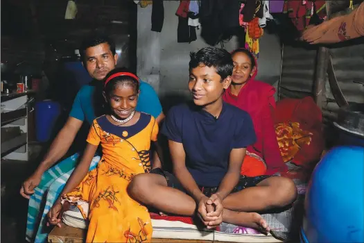  ?? (AP/Aijaz Rahi) ?? Jaidul Islam (left) sits with his wife, Pinjira Khatun (right), and their children, Jerifa (second left) and Raju, on July 20 inside their home in a poor neighborho­od in Bengaluru, India.