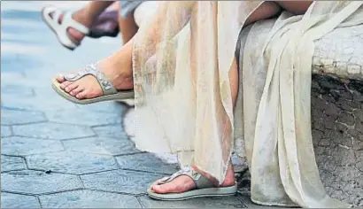  ?? LAURA GUERRERO ?? Una mujer sentada en un banco del paseo de Gràcia muestra unas chanclas de moda