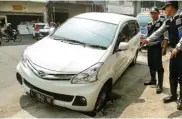  ?? RIZAL AHMAD/JAWA POS ?? BIKIN CELAKA: Petugas Dishub Surabaya membantu mengevakua­si mobil yang terperosok akibat lubang saluran dibiarkan tak berpenutup.