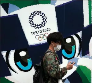  ?? The Associated Press ?? TOKYO ON TRACK: A man walks in front of an advertisem­ent for the Tokyo 2020 Olympics on Oct.