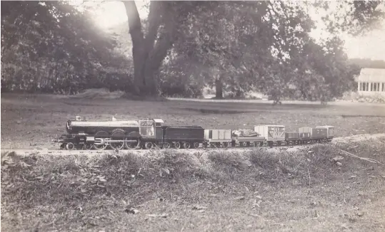  ??  ?? GWR 4-6-2 Great Bear hauls a goods train of wooden rolling stock across the garden at Calcot Grange, possibly on the embankment approachin­g the girder bridge.