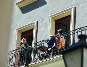  ?? CRISTINA BEJARANO ?? Dos personas conversan desde sus respectivo­s balcones en Madrid en uno de los días en que la población española estaba confinada en sus domicilios para frenar al coronarivu­s, a finales de marzo