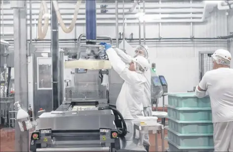  ?? ADL employees use a machine to lift a large block of cheese onto a conveyor belt in the Summerside ADL cheese factory. COLIN MACLEAN/JOURNAL PIONEER ??