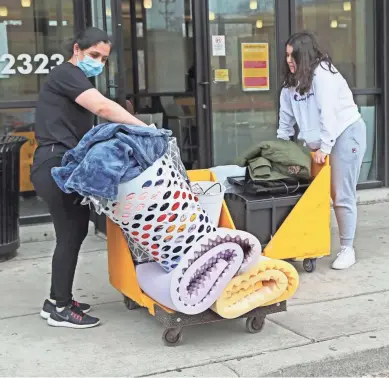  ?? MICHAEL SEARS/MILWAUKEE JOURNAL SENTINEL ?? Rano Atambaeua of Kenosha, left, helped move her daughter Sevinch Atambaeua out of the UW-Milwaukee Cambridge Commons dormitory on Friday. UWM is staggering the move-out dates for each dorm. The school predicts $7.5 million in refunds to students for room and board.