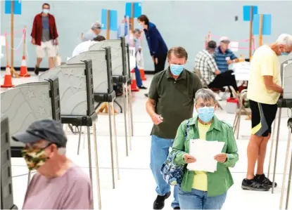  ?? RUSS DILLINGHAM/SUN JOURNAL VIA AP ?? Election workers and voters wear masks as a precaution against the spread of COVID-19 at a polling place during Maine’s primary election in July.