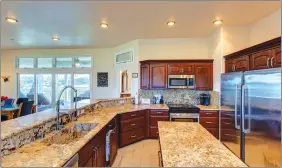  ??  ?? The well-appointed, up-to-date kitchen features a granite breakfast bar, counters and backsplash, large island, custom cabinetry and updated appliances.