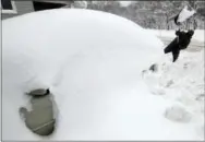  ?? THE ASSOCIATED PRESS ?? At left, Raid H digs his car out in his driveway Friday in Erie, Pa. At right, a man walks with his groceries in a cart in Erie. The cold weather pattern was expected to continue through the holiday weekend and likely longer, according to the National...