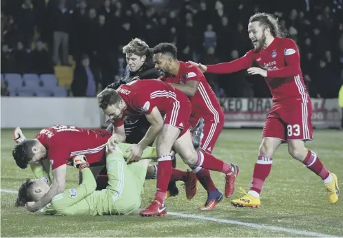  ??  ?? 0 Aberdeen goalkeeper Freddie Woodman is mobbed by his team-mates after his heroics in the penalty shoot-out against Kilmarnock.