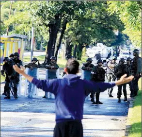  ?? AP/JUAN CARLOS HERNANDEZ ?? A man confronts Venezuelan national guardsmen Sunday outside the Paramacay military base in the city of Valencia near Caracas, where assailants reportedly were repelled after a pre-dawn attack.