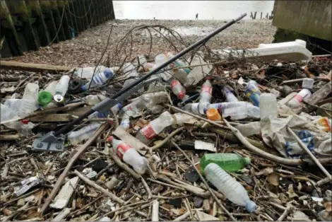  ?? MATT DUNHAM — THE ASSOCIATED PRESS FILE ?? Bottles and other plastics including a mop, lie washed up on the north bank of the River Thames in London. European Union officials agreed on Wednesday to ban some single-use plastics, such as disposable cutlery, plates and straws, in an effort to cut marine pollution. The measure will also affect plastic cotton buds, drink stirrers, balloon sticks, and single-use plastic and polystyren­e food and beverage containers.