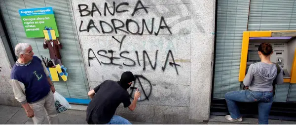  ??  ?? WRITE ON: A protester sprays ‘The banks are thieves and murderers’ on a wall in Madrid. Photo: REUTERS/Susana Vera