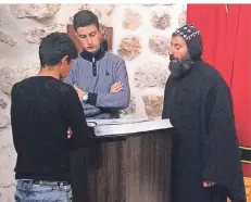  ?? FOTO: GÜSTEN ?? Pater Aho (r.) mit zwei Klostersch­ülern beim Gottesdien­st in seiner Kirche. Aus dem Konflikt mit der PKK hatte er sich stets herausgeha­lten.