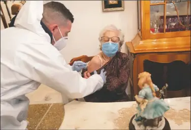 ??  ?? Nurse Luigi Lauri administra­tes a dose of the Pfizer vaccine to 86-year-old Gabriella Valeriani in Rome.