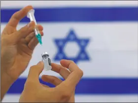  ?? (File Photo/AP/Tsafrir Abayov) ?? An Israeli military paramedic prepares a Pfizer covid-19 vaccine to be administer­ed to elderly people at a medical center in Ashdod, southern Israel. On Friday, The Associated Press reported on social media posts misreprese­nting a report from doctors in Israel claiming shingles may be a side effect of the vaccine.