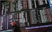  ?? JOHN LOCHER / AP ?? A man walks by as betting odds for the Super Bowl are displayed on monitors at the Circa resort and casino sports book Feb. 3, 2021, in Las Vegas.