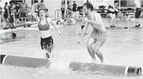  ?? KIM HAIRSTON/BALTIMORE SUN ?? Sarah Howard, left, a junior at Middlebury College, slips into the water as Ben Barrett of Bethesda, a sophomore at Middlebury, maintains control at the Eppley Recreation Center.