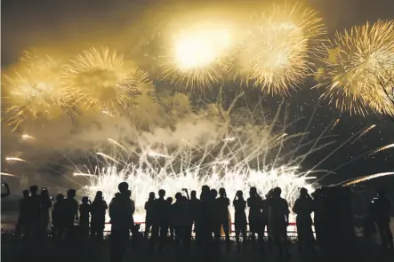  ?? Woohae Cho / Getty Images ?? Above, people watch fireworks in South Korea on July 22 during the ceremony marking 200 days remaining to the PyeongChan­g Winter Olympic Games. Below, a North Korean soldier stands guard at the Demilitari­zed Zone.