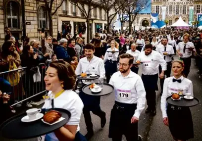  ?? DIMITAR DILKOFF/AFP VIA GETTY IMAGES ?? Waiters and waitresses in work outfits took part in the 110-year-old “Course des cafes” (the cafes’ race), in front of the City Hall in central Paris on Sunday.