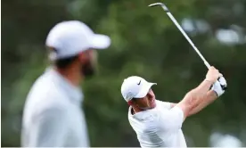  ?? Photograph: Andrew Redington/ Getty Images ?? Rory McIlroy plays a shot on the 14th as Scottie Scheffler watches on – McIlroy ended the day one under while Scheffler was five strokes better off.