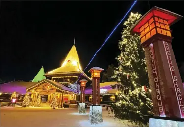  ?? JAMES BROOKS — THE ASSOCIATED PRESS ?? The Santa Claus Village tourist attraction lit with festive lights early in the morning Dec. 4in Rovaniemi, Finland. Workers at the winter wonderland on the edge of the Arctic Circle cut away at a frozen structure, put the final touches to an ice restaurant and hotel filled with frosty sculptures of snowmen, penguins and huskies. Finnish Lapland’s Christmas season is in full swing with operators reporting about 80% of 2019visito­r levels, which turned out to be a record-breaking year.