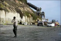  ?? DENIS POROY - THE ASSOCIATED PRESS ?? A San Diego County Sheriff’s deputy looks on as search and rescue personnel work at the site of a cliff collapse at a popular beach Friday, in Encinitas, Calif. At least one person was reportedly killed, and multiple people were injured, when an oceanfront bluff collapsed Friday at Grandview Beach in the Leucadia area of Encinitas, authoritie­s said.