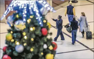  ?? JOHN SPINK / AJC ?? Passengers make their way past a giant Christmas tree at Hartsfield-Jackson Internatio­nal Airport on Friday. U.S. airlines expect to handle 51 million passengers from Dec. 15 through Jan. 4.