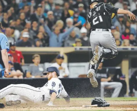  ?? Alex Gallardo, The Associated Press ?? Cory Spangenber­g slides under Rockies catcher Jonathan Lucroy and scores for the Padres on an infield single by Christian Villanueva during the sixth inning of Saturday night’s game at Petco Park in San Diego. The Rockies lost 5-0.