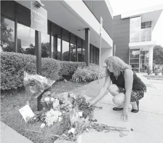  ??  ?? Kati Riek, a Golf Channel administra­tor, lays flowers at the makeshift memorial honouring Arnold Palmer at his parking spot at the studio on Monday in Orlando, Florida.