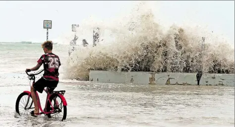  ?? DPA-BILD: TRAINOR JR ?? Ein Junge radelt in Key West, Florida (USA) an der überschwem­mten UferCromen­ade entlang.