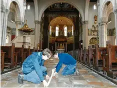  ?? Foto: Silvio Wyszengrad ?? Vorbereitu­ngen für die ersten Gottesdien­ste: Jürgen Massinger und Christoph Hausladen (v.li.) bringen am Boden der Pferseer Herz-Jesu-Kirche Pfeile an, damit Gottesdien­stbesucher Abstand halten können.